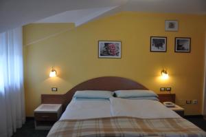 um quarto com uma cama e uma parede amarela em Hotel Residence Rosa em San Lugano