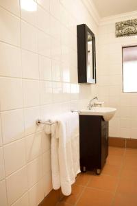 a white bathroom with a sink and towels at Remhoogte Mountain Lodge in Jacksonstuin