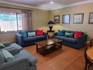 a living room with two blue couches and a table at Remhoogte Mountain Lodge in Jacksonstuin