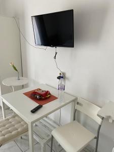 a white table and chairs with a television on a wall at Δωματια ΞΑΝΘΟΥΛΑ in Amaliapoli