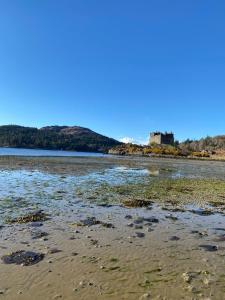 a view of a beach with a castle in the background at Brackenbrae Holiday Cottage in Acharacle