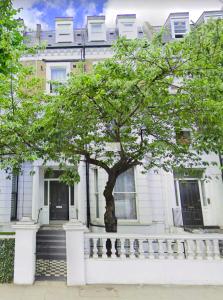 Una casa blanca con un árbol delante. en Stylish Apartment Opposite Westfields en Londres