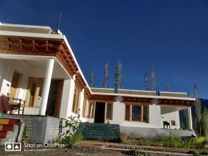a large white house with a blue sky in the background at Natures View Residency in Hundar
