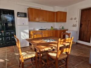 Casa El Banco في Iznate: مطبخ مع طاولة خشبية وكراسي خشبية