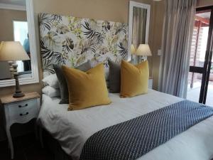 a bedroom with a large bed with yellow pillows at Remhoogte Mountain Lodge in Jacksonstuin