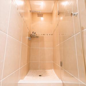 y baño con ducha de azulejos beige. en Poolside Cottage, en Johannesburgo