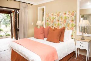 a bedroom with a large bed with orange pillows at Remhoogte Mountain Lodge in Jacksonstuin
