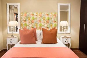 a bedroom with a bed with a large headboard and two mirrors at Remhoogte Mountain Lodge in Jacksonstuin