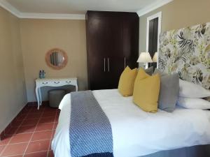 a bedroom with a large white bed with yellow pillows at Remhoogte Mountain Lodge in Jacksonstuin