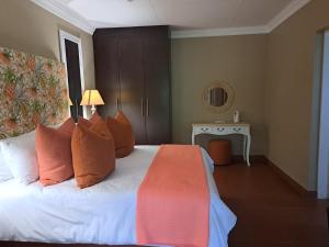 a bedroom with a bed with orange pillows and a table at Remhoogte Mountain Lodge in Jacksonstuin