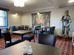 uma sala de jantar com mesas e uma estátua de um cavaleiro em Kings Arms Hotel em Lockerbie