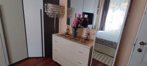 a room with a dresser with a vase of flowers on it at Azzurra holiday home - 850 m al mare - 75 mq - balconata vivibile - wi-fi - pay tv gratis - posteggio auto condominiale non assegnato in Rapallo