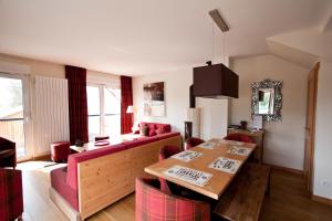 a living room with a wooden table and red chairs at Appart'hôtels La Maison du Tigre in Stutzheim