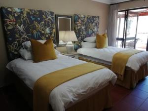 a hotel room with two beds with yellow pillows at Remhoogte Mountain Lodge in Jacksonstuin