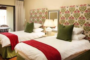 a bedroom with two beds with red and green pillows at Remhoogte Mountain Lodge in Jacksonstuin