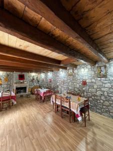 a dining room with tables and chairs and a stone wall at Guest House Rrashkadoli in Theth