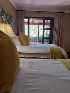 two beds in a hotel room with a window at Remhoogte Mountain Lodge in Jacksonstuin