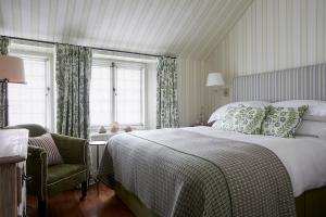 a bedroom with a bed and a chair and a window at Hotel Tresanton in Saint Mawes
