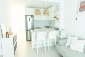 a white kitchen with a couch and a kitchen island at Lindamar Canteras Beach House in Las Palmas de Gran Canaria