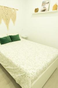 a white bed in a white room with green pillows at Lindamar Canteras Beach House in Las Palmas de Gran Canaria