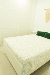 a white bed in a white room with green pillows at Lindamar Canteras Beach House in Las Palmas de Gran Canaria
