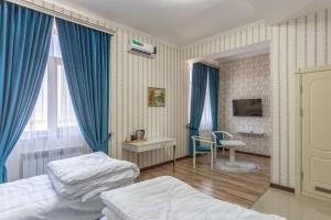 een slaapkamer met 2 bedden, een bureau en een televisie bij Muxlis Hotel in Tasjkent