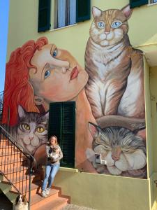 une femme debout devant une fresque de chats dans l'établissement B&B I TRE GATTI, à Pesaro