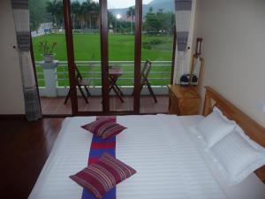 Schlafzimmer mit einem Bett und Blick auf einen Golfplatz in der Unterkunft Mai Chau Valley View Hotel in Mai Châu