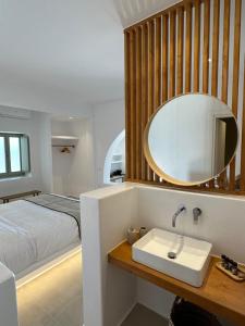Quattro Venti Suites Mykonos في تورلوس: حمام مع حوض وسرير ومرآة