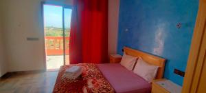um quarto com uma cama com uma cortina vermelha e uma janela em chez JM saida em Ourika
