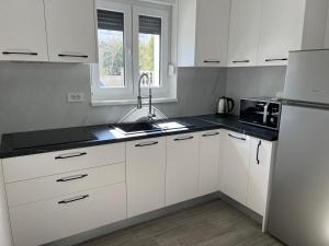 La cuisine blanche est équipée d'un évier et d'un réfrigérateur. dans l'établissement Apartment Irene, à Vir 16 autres photos