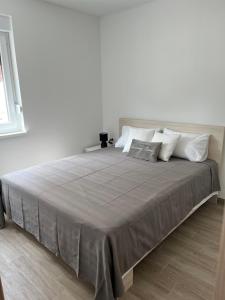 a white bedroom with a large bed with white pillows at Apartment Irene in Vir