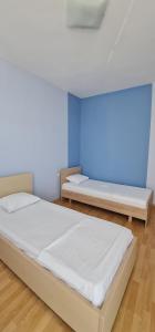 two beds in a room with a blue wall at Summer Breeze Apartment Saranda in Sarandë