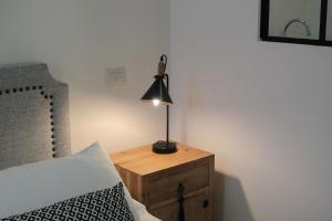 a lamp on a wooden night stand next to a bed at Emperador in Alghero