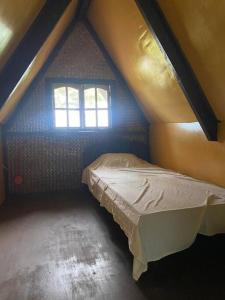 ein Schlafzimmer mit einem Bett im Dachgeschoss mit einem Fenster in der Unterkunft Auntie Mina's Beach Cabins in Puerto Princesa