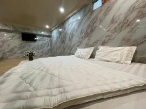 Centralhome 2 في Plei Brêng: سرير أبيض كبير في غرفة ذات جدار من الرخام