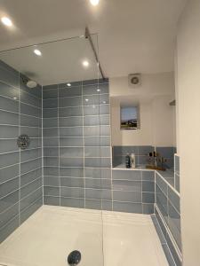 ein Bad mit einer Dusche und blauen Fliesen in der Unterkunft Rivulet Cottage in Pateley Bridge