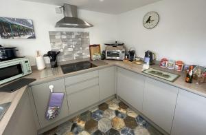 eine Küche mit weißen Schränken und einer Uhr an der Wand in der Unterkunft Rivulet Cottage in Pateley Bridge