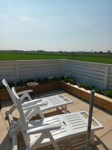 two white chairs and tables on a patio at Strandrose in Friedrichskoog