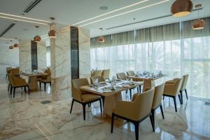un restaurante con mesas, sillas y ventanas grandes en Alberni Jabal Hafeet Hotel Al Ain, en Al Ain