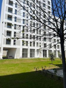 a large white building with a tree in front of it at Comfy Nest Apartment- free parking in Tirana
