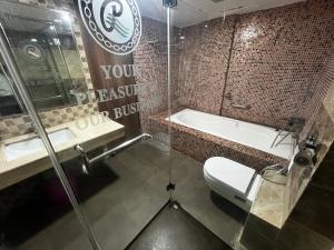 a bathroom with a toilet and a sink and a tub at Ramee Guestline Hotel Bangalore in Attibele