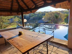 a wooden table on a patio with a view of a lake at Stone Meadows Country Estate-NV51 in Magaliesburg