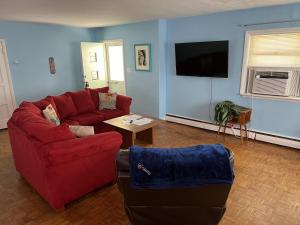 a living room with a red couch and a table at Beach Front on the Bay in our Rustic, Pet Friendly Cottage home in North Camellia Acres