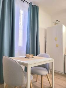 una mesa de comedor y sillas con cortinas azules en Chez Mélanie et Rodolphe en La Ciotat
