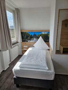 a bedroom with a white bed with a large window at Stadthotel Kassel in Kassel