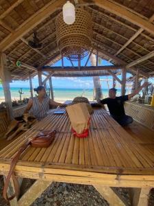 três homens sentados numa mesa de piquenique na praia em Balay Asiano Cabin em Puerto Princesa