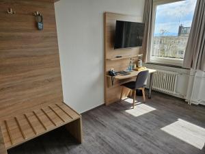 um quarto de hotel com uma secretária, uma televisão e uma janela em Stadthotel Kassel em Kassel