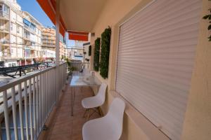 balkon z 2 białymi krzesłami i stołem w obiekcie RONDA Centro Levante Beach w mieście Benidorm