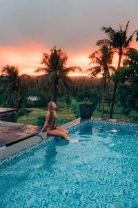 a woman sitting on the edge of a swimming pool at Lexias Hostel and Workspace - Siargao in Catagnan
